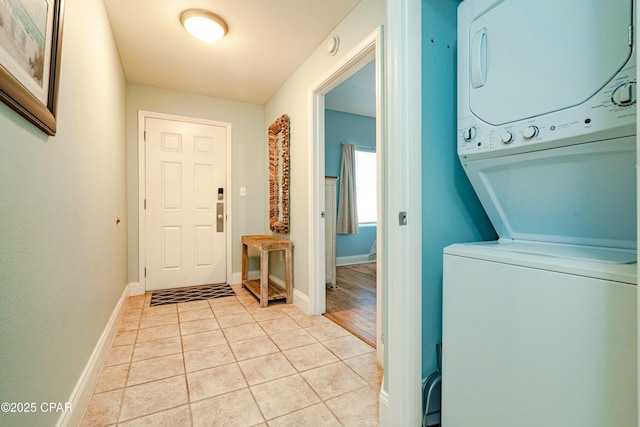 laundry area with stacked washer and clothes dryer and light tile patterned flooring