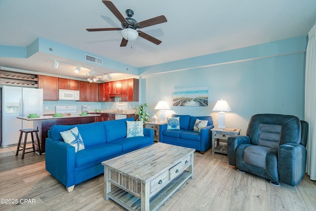 living room with ceiling fan, rail lighting, and light hardwood / wood-style flooring