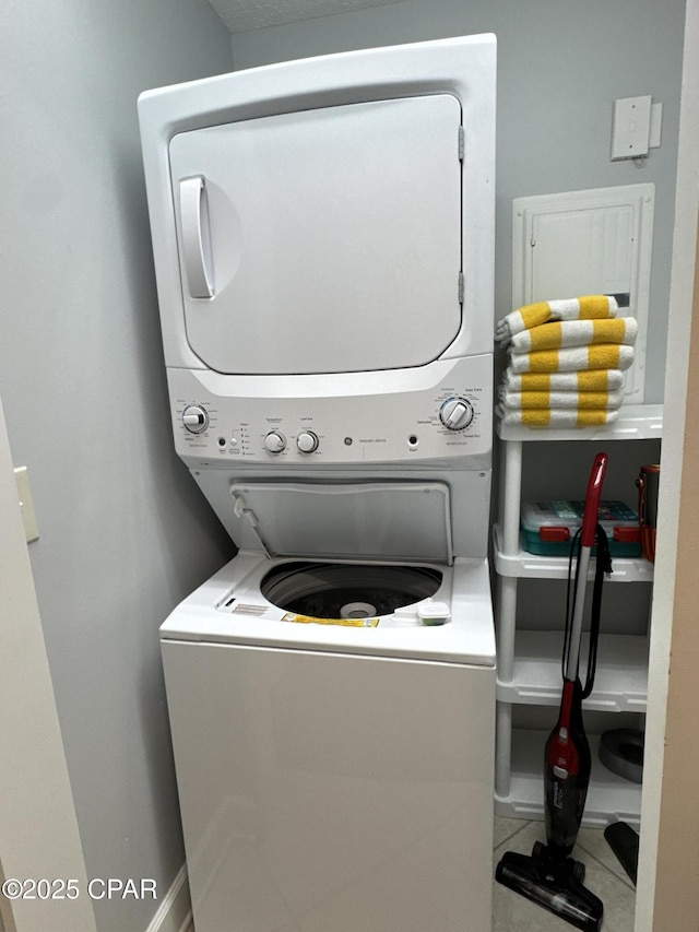 clothes washing area featuring tile patterned floors and stacked washer / dryer