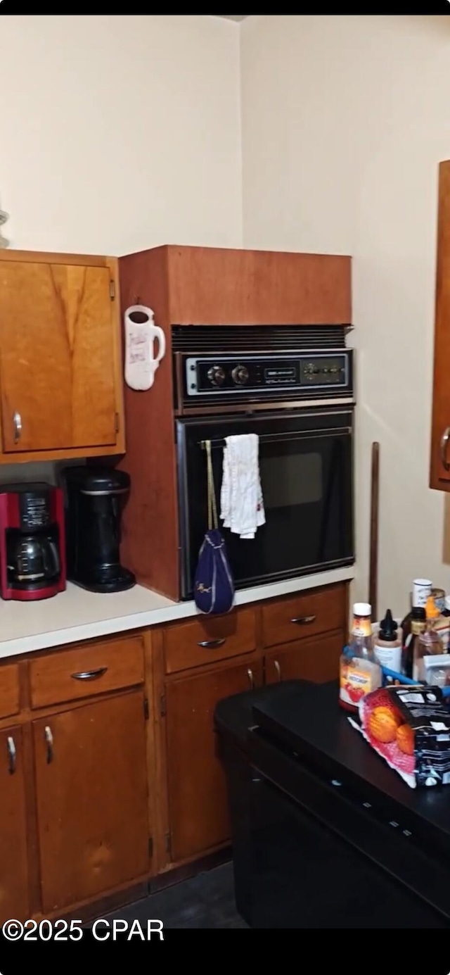 kitchen with brown cabinetry, light countertops, and oven