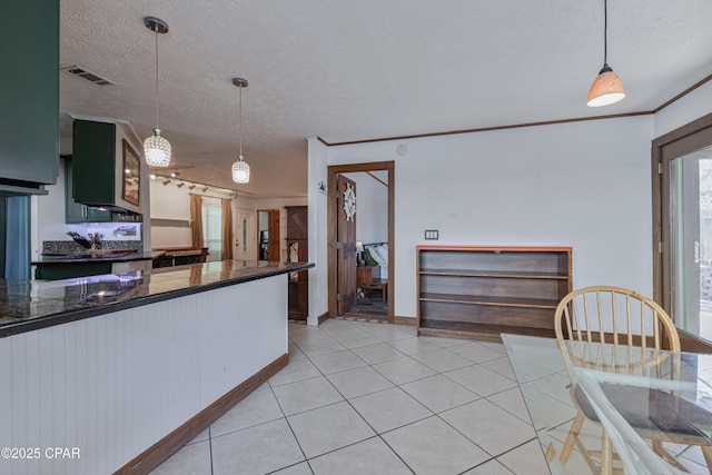 kitchen featuring light tile patterned floors, ornamental molding, a textured ceiling, decorative light fixtures, and kitchen peninsula