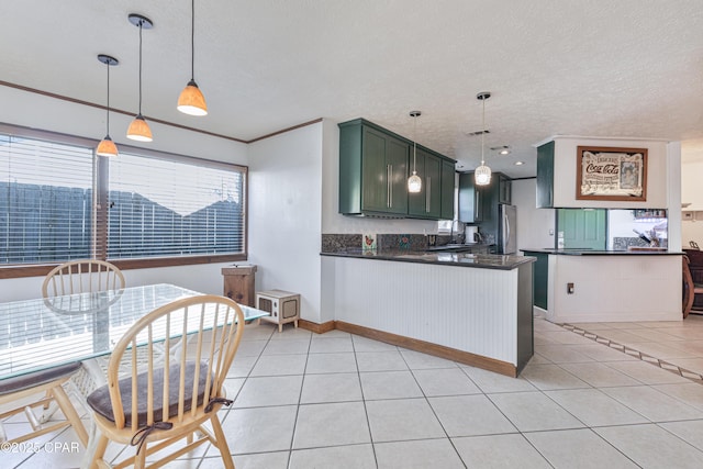 kitchen featuring light tile patterned flooring, green cabinetry, decorative light fixtures, stainless steel fridge, and kitchen peninsula