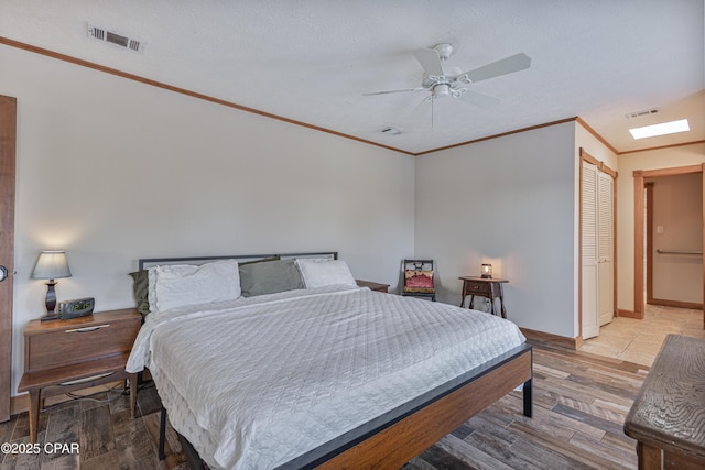 bedroom featuring ornamental molding, a textured ceiling, ceiling fan, and light hardwood / wood-style flooring