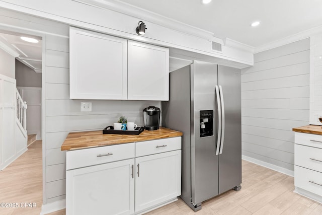 kitchen with white cabinets, butcher block counters, stainless steel fridge, and light hardwood / wood-style flooring