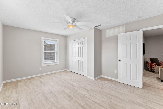 unfurnished bedroom featuring ceiling fan, light hardwood / wood-style floors, a closet, and a textured ceiling