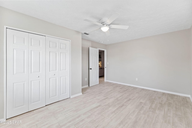 unfurnished bedroom with ceiling fan, a closet, a textured ceiling, and light wood-type flooring