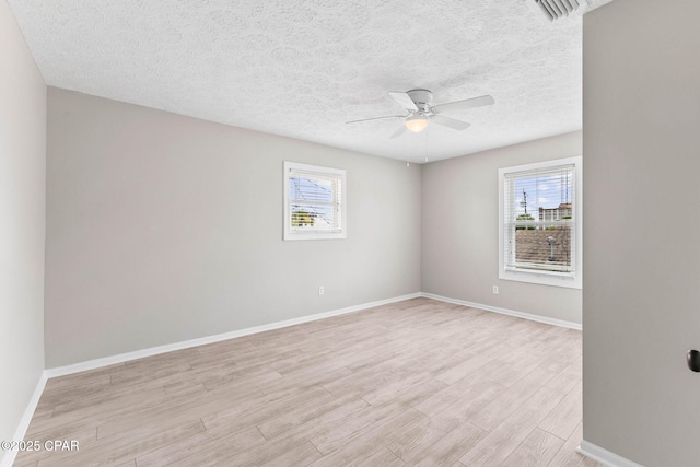 spare room featuring ceiling fan, plenty of natural light, light hardwood / wood-style flooring, and a textured ceiling