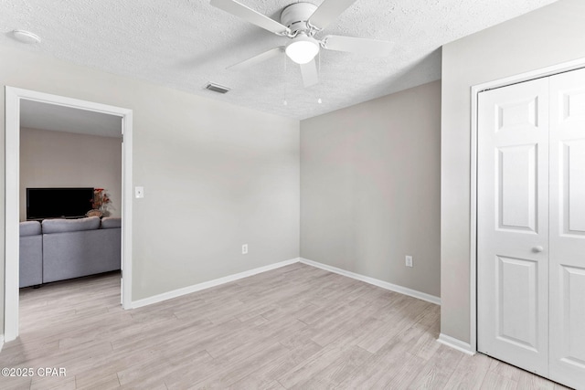 unfurnished bedroom with light hardwood / wood-style floors, a closet, and a textured ceiling