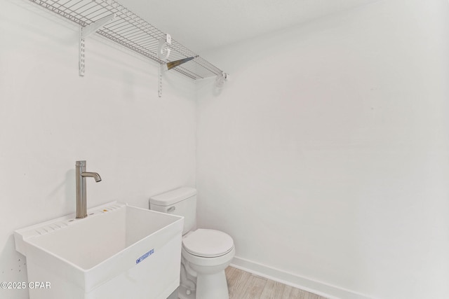 bathroom featuring toilet, sink, and hardwood / wood-style floors