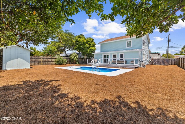 back of house featuring a fenced in pool and a storage unit