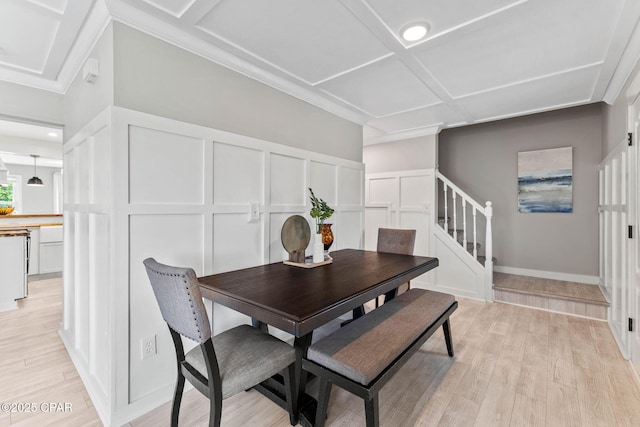 dining area featuring coffered ceiling and light hardwood / wood-style floors