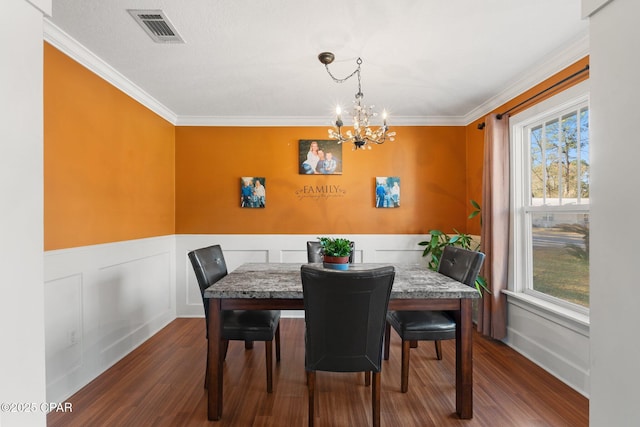 dining area with an inviting chandelier, ornamental molding, and dark hardwood / wood-style flooring