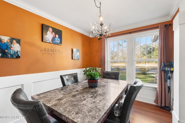 dining room with hardwood / wood-style floors, ornamental molding, and a chandelier