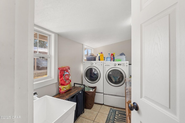 laundry area featuring washer and dryer, a textured ceiling, and light tile patterned flooring