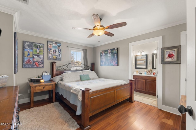 bedroom with hardwood / wood-style flooring, ceiling fan, connected bathroom, and crown molding