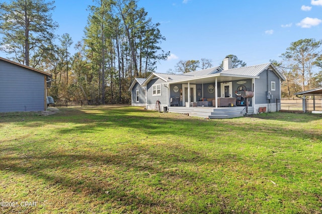 rear view of house featuring covered porch and a lawn