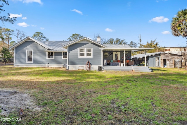 rear view of property with an outdoor structure and a yard