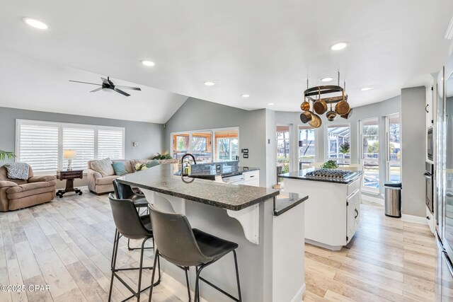 kitchen with sink, dark stone countertops, a kitchen island, stainless steel appliances, and white cabinets