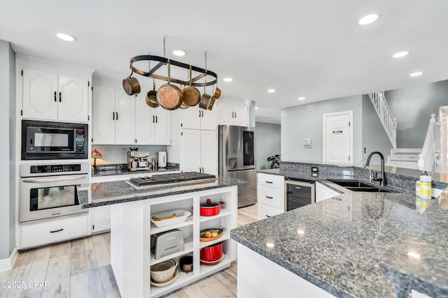 kitchen with sink, beverage cooler, white cabinets, and appliances with stainless steel finishes