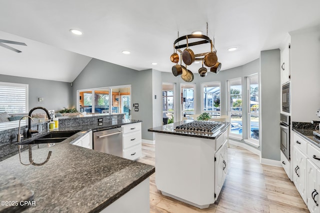 kitchen with a sink, a kitchen island, recessed lighting, appliances with stainless steel finishes, and lofted ceiling