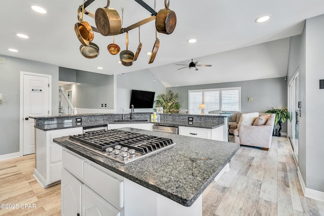 kitchen featuring a sink, a kitchen island, open floor plan, appliances with stainless steel finishes, and light wood finished floors