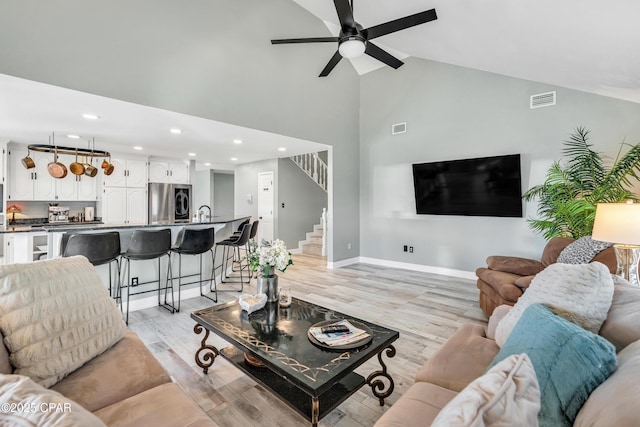 living area featuring stairs, baseboards, visible vents, and light wood-type flooring