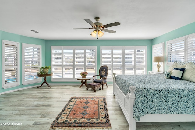 bedroom featuring light wood finished floors, visible vents, baseboards, and a ceiling fan