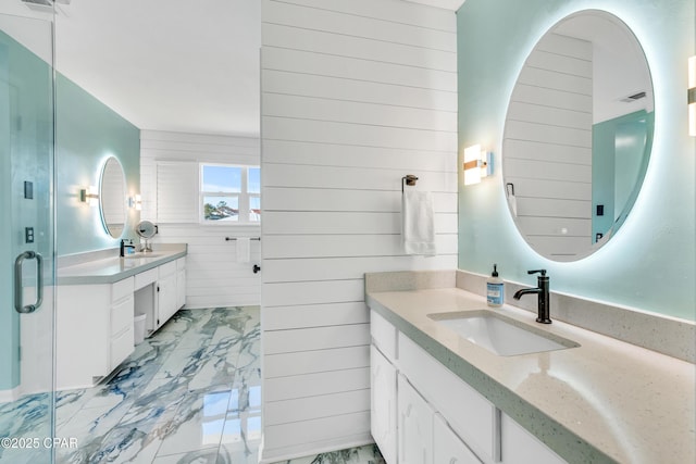 bathroom with wooden walls, marble finish floor, a shower stall, and vanity