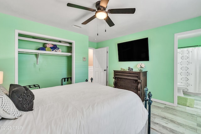 bedroom with wood finished floors, visible vents, ceiling fan, a closet, and ensuite bathroom