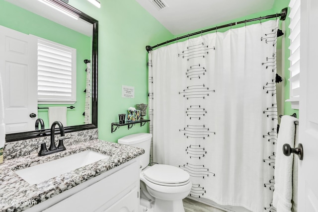 bathroom featuring a shower with shower curtain, visible vents, toilet, and vanity