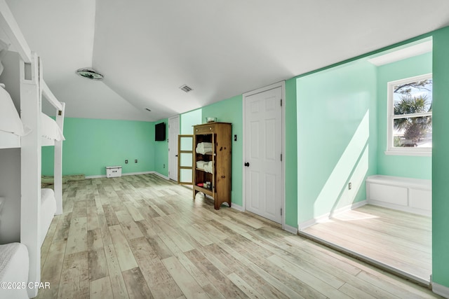 interior space with vaulted ceiling, baseboards, visible vents, and light wood finished floors