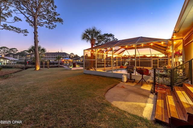 yard at dusk featuring a lanai, a patio area, and an outdoor pool