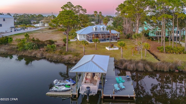 dock area with glass enclosure, a lawn, a water view, and boat lift