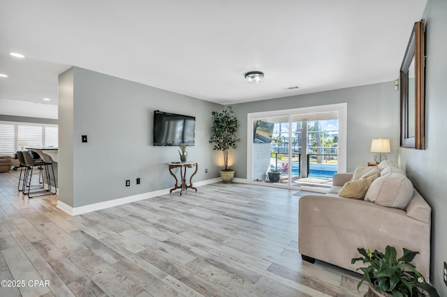 living room featuring recessed lighting, light wood-style floors, visible vents, and baseboards