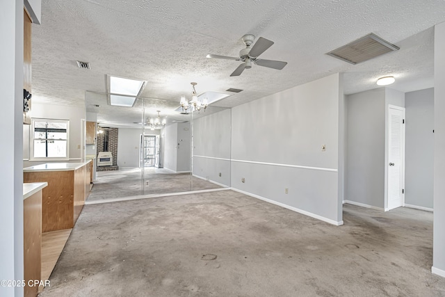 unfurnished room with ceiling fan with notable chandelier and a textured ceiling