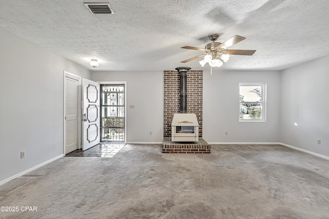 unfurnished living room with ceiling fan, a textured ceiling, carpet, and a wood stove