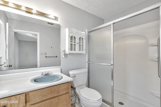 bathroom featuring a shower with door, vanity, a textured ceiling, and toilet