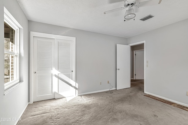 unfurnished room with ceiling fan, light carpet, and a textured ceiling