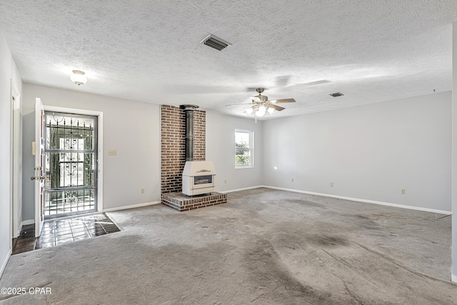 unfurnished living room featuring ceiling fan, carpet flooring, a textured ceiling, and a wood stove