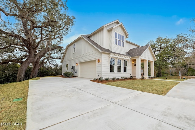 view of front of house with concrete driveway, roof with shingles, a front yard, and board and batten siding