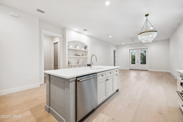 kitchen with light countertops, a kitchen island with sink, a sink, white cabinetry, and dishwasher