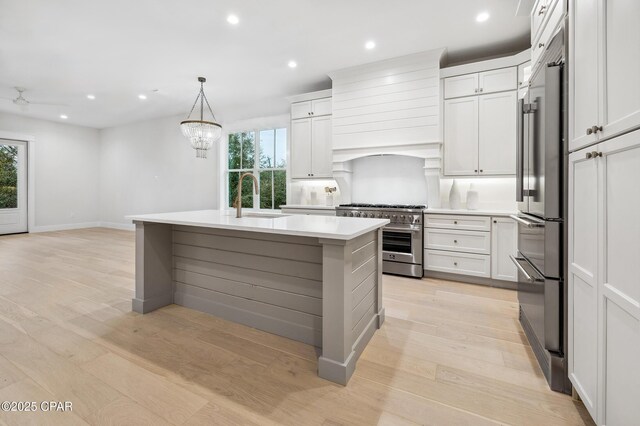 kitchen with light countertops, premium appliances, a sink, and white cabinetry