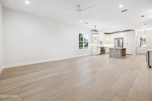 unfurnished living room featuring baseboards, light wood-type flooring, a ceiling fan, and recessed lighting