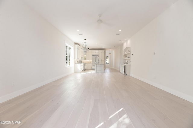 unfurnished living room featuring baseboards, recessed lighting, light wood-style flooring, and built in features