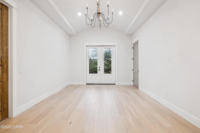 foyer entrance with french doors, lofted ceiling, a chandelier, light wood-type flooring, and baseboards