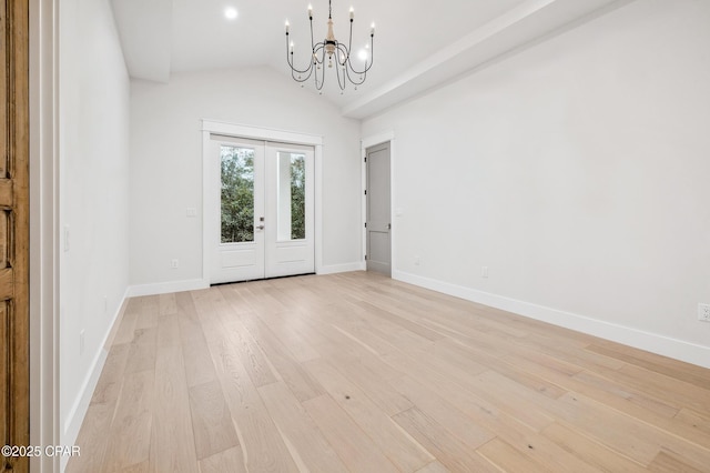 spare room featuring lofted ceiling, a notable chandelier, baseboards, french doors, and light wood-type flooring