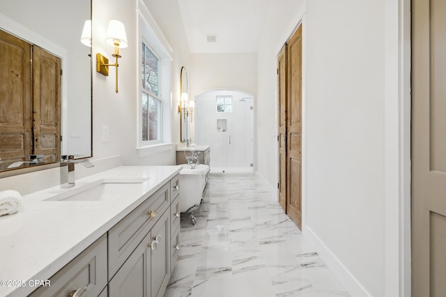 bathroom with marble finish floor, a stall shower, vanity, a freestanding tub, and baseboards