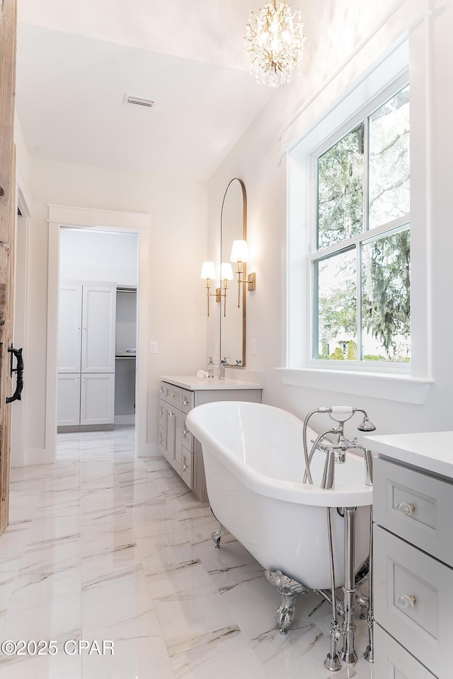 bathroom with visible vents, a soaking tub, marble finish floor, a spacious closet, and vanity