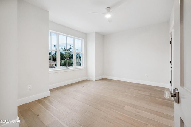 spare room with baseboards, ceiling fan, and light wood finished floors