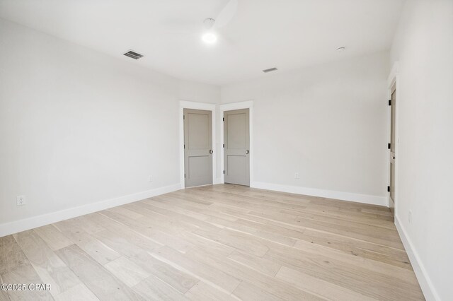 unfurnished room featuring light wood-type flooring, baseboards, and visible vents